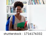 Pretty afro american female student with backpack and paperwork at classroom of university