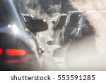 Blurred silhouettes of cars surrounded by steam from the exhaust pipes. Traffic jam 