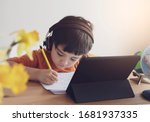 Kid online distance,Asian Child using tablet technology for homework,Schoolboy wearing headphones listen and reading information from internet, Kindergarten learning about world environment lesson.
