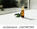 Amber bottle with serum or essential oil. Natural organic cosmetic, aromatherapy message oil. A drop of oil at the end of a pipette