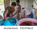 Small photo of DHAKA, BANGLADESH - MAY 23, 2016: Textile factory dyehouse where three underaged children are mixing the local garments with dyestuff to color the garments