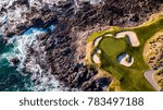 Small photo of Drone view of a golf course next to the ocean with waves hitting the rocks on the seashore