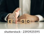 Small photo of The businessman puts his hand between wooden blocks with the words Ego and GO. Self-appraisal, Be someone else, alter ego for success Business. EGO is the enemy. true personality concepts.