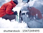 Confused man putting snow chains on car tire
