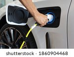 Man hand is holding Electric car charging connect to elecric car on charge station, Electric mobility environment friendly 	