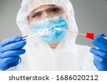 Small photo of Medical healthcare NHS technician holding COVID-19 swab collection kit,wearing white PPE protective suit mask gloves,test tube for taking OP NP patient specimen sample,PCR DNA testing protocol process