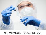 Small photo of Medical worker filling syringe with vaccination shot dose,nurse wearing protective equipment preparing booster dose of Coronavirus jab,COVID-19 immunization procedure in a hospital or clinic facility