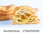 A closeup image  of puff pastry in the incision with blown large crunchy layers of golden brown crust on top visible. Located on a white background