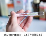 a thermometer with a high temperature in the hand against the background of medications