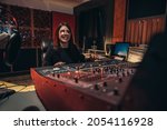 Small photo of Young woman music producer working on a mixing soundboard while in her studio