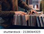 Small photo of Close shot of a woman hands browsing records in the vinyl record store. Audiophile and music lover. Vintage Vinyl LP In Records Shop.