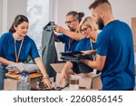 Small photo of Group of diverse people working in charitable foundation. Volunteer separating donation stuff. Volunteers sort donations during food drive. Focus on a middle aged man preparing clothes. Copy space.