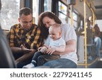 Small photo of Young mother and father sitting with their son in a bus while riding in a city. Boy is sitting in mother lap. Plus size mom holding her child in public transportation while father sitting next to them