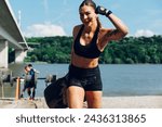 Small photo of Woman athlete celebrating with a hand up in the air while partake in one of the events of an obstacle course race. Female working out outside. Sport competition and OCR race.