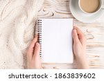 Pov top overhead above close up view photo of woman hands holding open note pad near cup of hot beverage and sweater