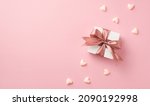 Small photo of Top view photo of valentine's day decorations white giftbox with pink silk ribbon bow and small hearts on isolated pastel pink background with copyspace