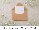 Top view photo of woman's day composition open craft paper envelope with paper card and white gypsophila flowers on isolated textured grey concrete background with empty space