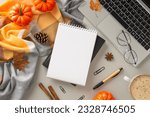 Coziness of working from home with laptop concept. Above view photo of notebook surrounded by blanket, pumpkins, pinecones and spices, office supplies, glasses and laptop on isolated grey background