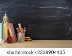 Small photo of School supplies layout. Side view photo of desk setup with pencils organizer, ruler, books, red apple, mannequin body, and more on chalkboard background. Great for educational content or advertising