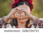 Ukrainian woman in traditional embroidery vyshyvanka dress making sign of shape heart. Ukraine, volunteering, donation help and love concept. High quality photo