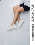 Small photo of Women shoes. Close up of female legs in leather white loafers. New spring-summer collection of women's leather shoes