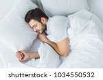 top view of bearded man sleeping on bed in bedroom