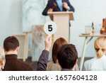 back view of buyer showing auction paddle with number five during auction