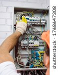 Small photo of Selective focus of electrician in glove holding pliers and turning on toggle switches of electrical box