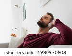 relaxing man listening music in wireless headphones with closed eyes