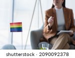 small lgbt flag near cropped psychologist with digital tablet on blurred background