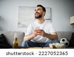cheerful man using smartphone near bottle of beer and tasty food on blurred foreground