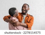 Positive african american son hugging mature father in living room