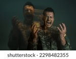 Small photo of Long exposure of serviceman in uniform screaming while suffering from dissociation disorder isolated on dark grey