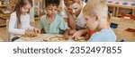 Small photo of teacher using didactic material while playing with multiethnic kids in montessori school, banner