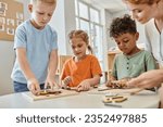 Small photo of interracial kids playing with didactic montessori material near teacher in school, learn and play
