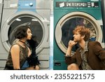 side view of trendy multiethnic couple looking at each other near washing machines in public laundry