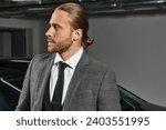 handsome red haired man with ponytail in elegant suit posing and looking away, business man