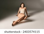 Small photo of alluring asian woman with short hair posing in corset and beige fishnet tights on grey background