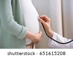 Cropped shot of doctor with stethoscope listening belly of pregnant woman 