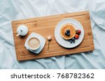 top view of breakfast in bed with tasty pancakes and coffee on wooden tray