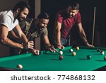 group of young handsome men playing in pool at bar 