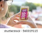 Girl holding a smartphone with a 50% discount advertising on the screen. Marketing, ecommerce, cell phone publicity.