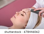 Small photo of Woman getting cleansing rejuvenating facial treatment in a beauty SPA salon. Exfoliation, Rejuvenation And Hydration. Cosmetology, ionisation, diamond procedures. Close up, selective focus.