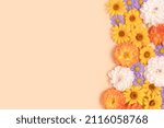 Colorful arnica and dahlia flowers texture on a beige background with copyspace. Nature concept for greeting cards. Springtime frame.