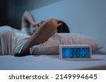Small photo of woman have insomnia on the bed selective focus on alarm clock at three in the morning.