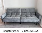 Small photo of Living room interior with front view of futon couch gray sofa sofabed with microfiber velvet fabric in modern apartment home house