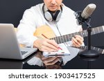 Small photo of young asian male songwriter writing a hit song while playing acoustic guitar. songwriting concept