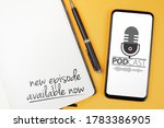 podcasting concept, text NEW EPISODE AVAILABLE NOW written on note pad and smartphone with podcast player mockup on orange desk