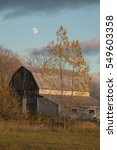 Small photo of An old gambrel roofed barn in the autumn with yellow leaved aspens and the moon rising.