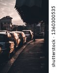 Small photo of GENOVA, ITALY - 30 MAY 2018: View from behind of parked cars on the street at sunset with beautiful sun light. Vintage flim grain tone